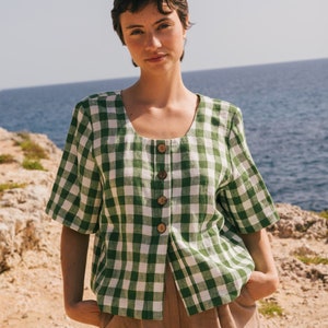 May include: A green and white gingham button-up shirt with short sleeves. The shirt is made of a lightweight fabric and has a relaxed fit.