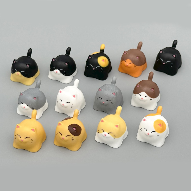 May include: A set of 14 small, colorful, ceramic cat figurines. Each cat is in a different pose and has a different color and pattern. The cats are all about 2 inches tall.