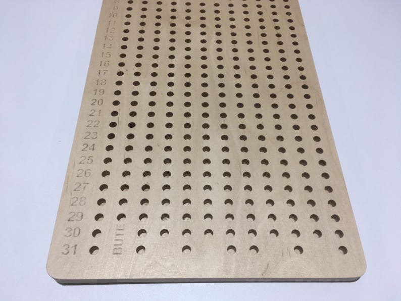 May include: A wooden pegboard with 31 rows of holes, numbered from 1 to 31. The pegboard is made of light wood and has a smooth surface. The holes are evenly spaced and are about 1.2 cm in diameter.