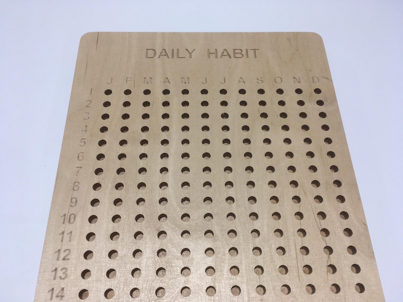 May include: A wooden daily habit tracker with a grid of holes for marking days of the month. The months are labelled across the top: January, February, March, April, May, June, July, August, September, October, November, December.