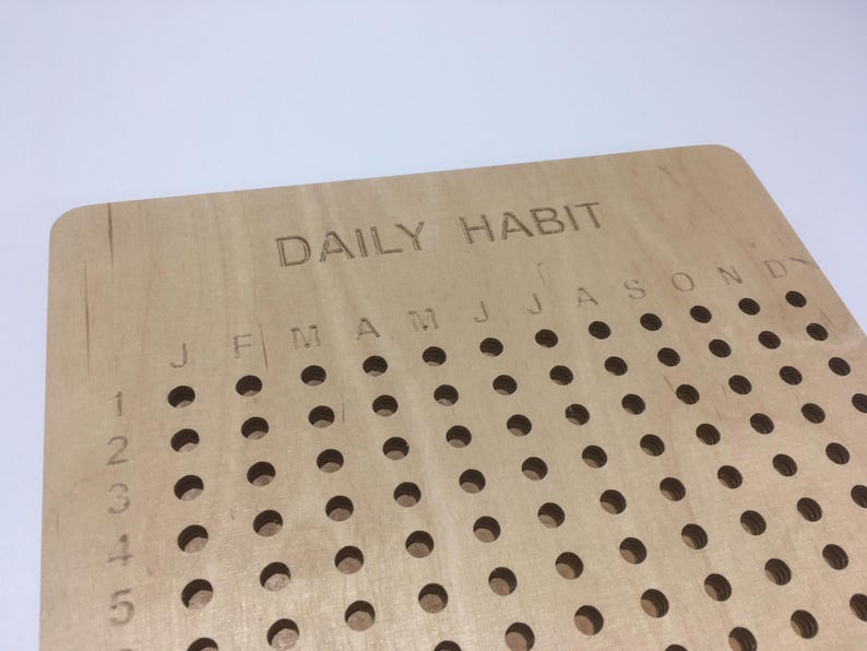 May include: A wooden daily habit tracker with holes for marking off days. The tracker has the months of the year labelled across the top and numbers 1 through 5 down the side.