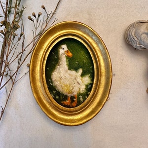 Peinture à l'huile miniature d'un canard, encadrée dans un cadre ovale doré fait main.
