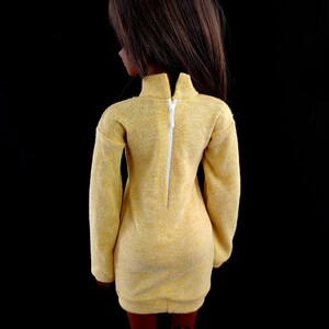 May include: A yellow dress with a white zipper down the back. The dress has long sleeves and a fitted silhouette.