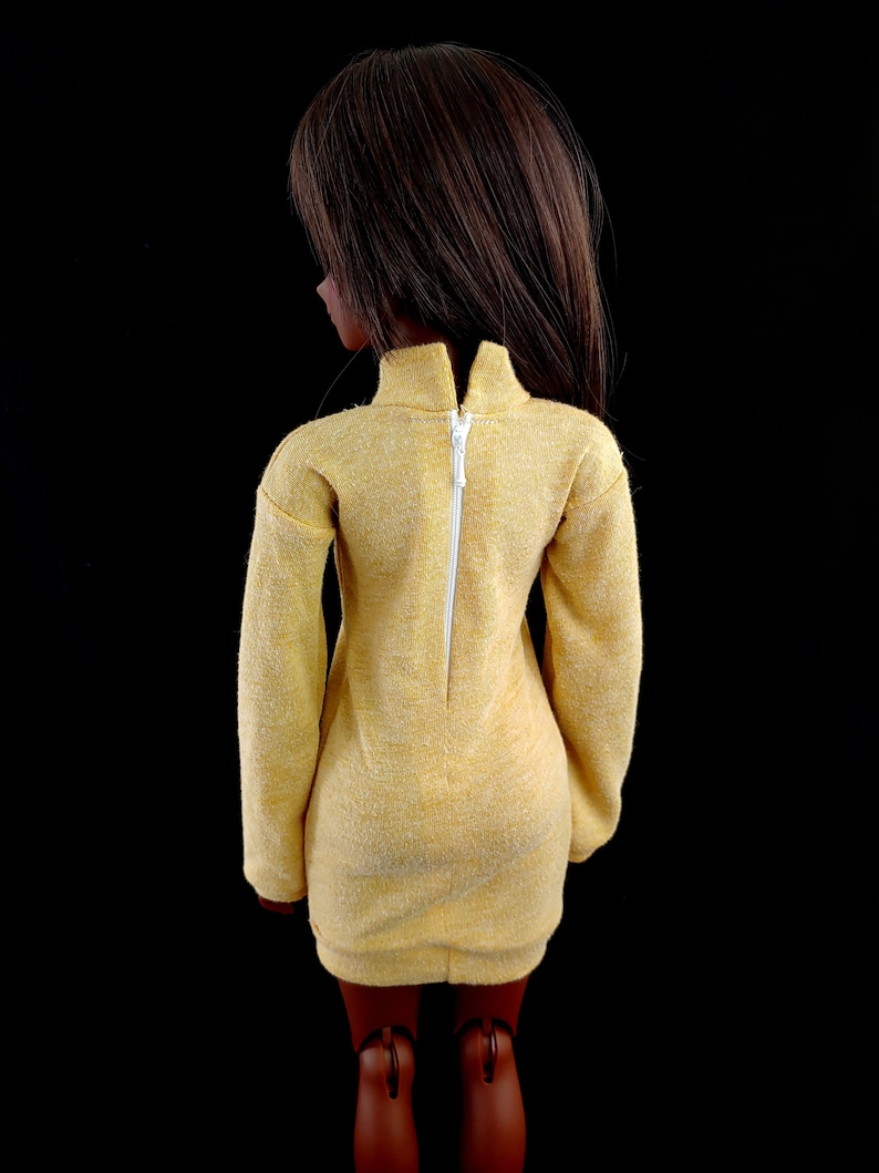 May include: A yellow dress with a white zipper down the back. The dress has long sleeves and a fitted silhouette.