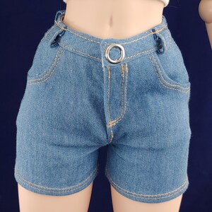 May include: A pair of denim shorts with a light blue wash. The shorts have a button and zipper closure, belt loops, and two front pockets.