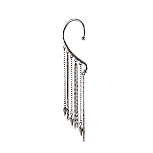Peut inclure: Un ear cuff argenté avec un design incurvé qui s'accroche à l'oreille. Plusieurs chaînes de différentes longueurs pendent de la manchette, certaines se terminant par des breloques pointues en forme de cône. Le bijou est sur fond blanc.