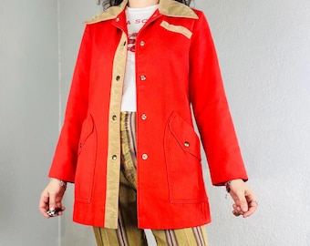 Puede incluir: Chaqueta vintage roja brillante con cuello y ribetes de pana color beige. La chaqueta tiene cierre de botones, dos bolsillos delanteros y botones dorados. Se combina con pantalones a rayas y una camiseta blanca.