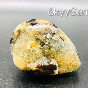 May include: A yellow and brown crystal with a rough, textured surface. The crystal has a unique, organic shape and is a natural specimen.
