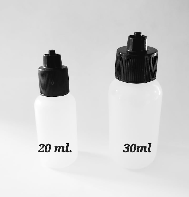 May include: Two clear plastic bottles with black caps. The smaller bottle is labeled "20 ml." and the larger bottle is labeled "30ml." The bottles are cylindrical with a rounded base and a black, ribbed cap with a small nozzle.