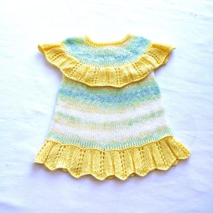 May include: A yellow and green knitted baby dress with a ruffled neckline and hem.
