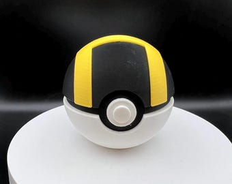 May include: A black and yellow Poke Ball with a white center button. The Poke Ball is a popular collectible toy.