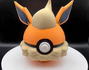 May include: A 3D printed orange and tan Pokemon figure of a Vaporeon, a water-type Pokemon. The figure has blue ears and a white Pokeball on its chest.