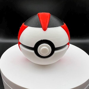 May include: A white, red, and black Poke Ball with a black button in the center. The Poke Ball is a popular collectible toy.