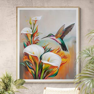 Könnte beinhalten: Ein gerahmter Kunstdruck mit einem lebhaften Kolibri in der Nähe weißer Calla-Lilien. Das Kunstwerk zeigt eine farbenfrohe Palette aus Grün-, Orange- und Gelbtönen mit einem neutralen Hintergrund. Der Kolibri hat schillernde Federn.