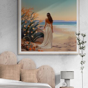 May include: A framed painting of a woman in a white dress standing on a beach with her back to the viewer. The woman is looking out at the ocean. There are tall green plants in the foreground and the beach is sandy with blue water in the background. The painting is signed "Patricia Salla".