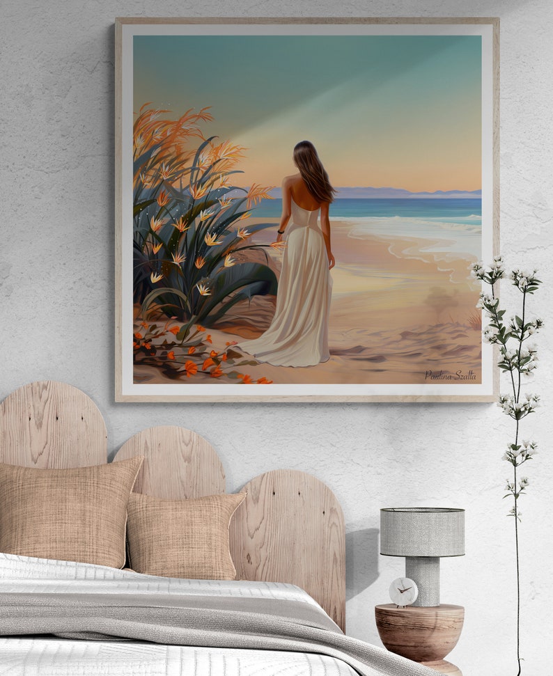 May include: A framed painting of a woman in a white dress standing on a beach with her back to the viewer. The woman is looking out at the ocean. There are tall green plants in the foreground and the beach is sandy with blue water in the background. The painting is signed "Patricia Salla".