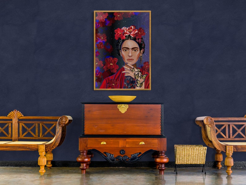 May include: A framed painting of Frida Kahlo with a floral crown and butterflies on her hands. The painting is set against a dark blue wall with two wooden benches and a wooden chest.