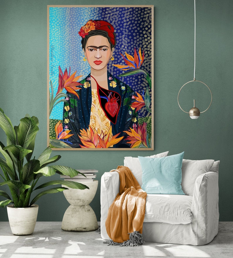 May include: A colorful painting of Frida Kahlo with a bird of paradise flower behind her. The painting is framed in wood and has a blue and white background with white dots.