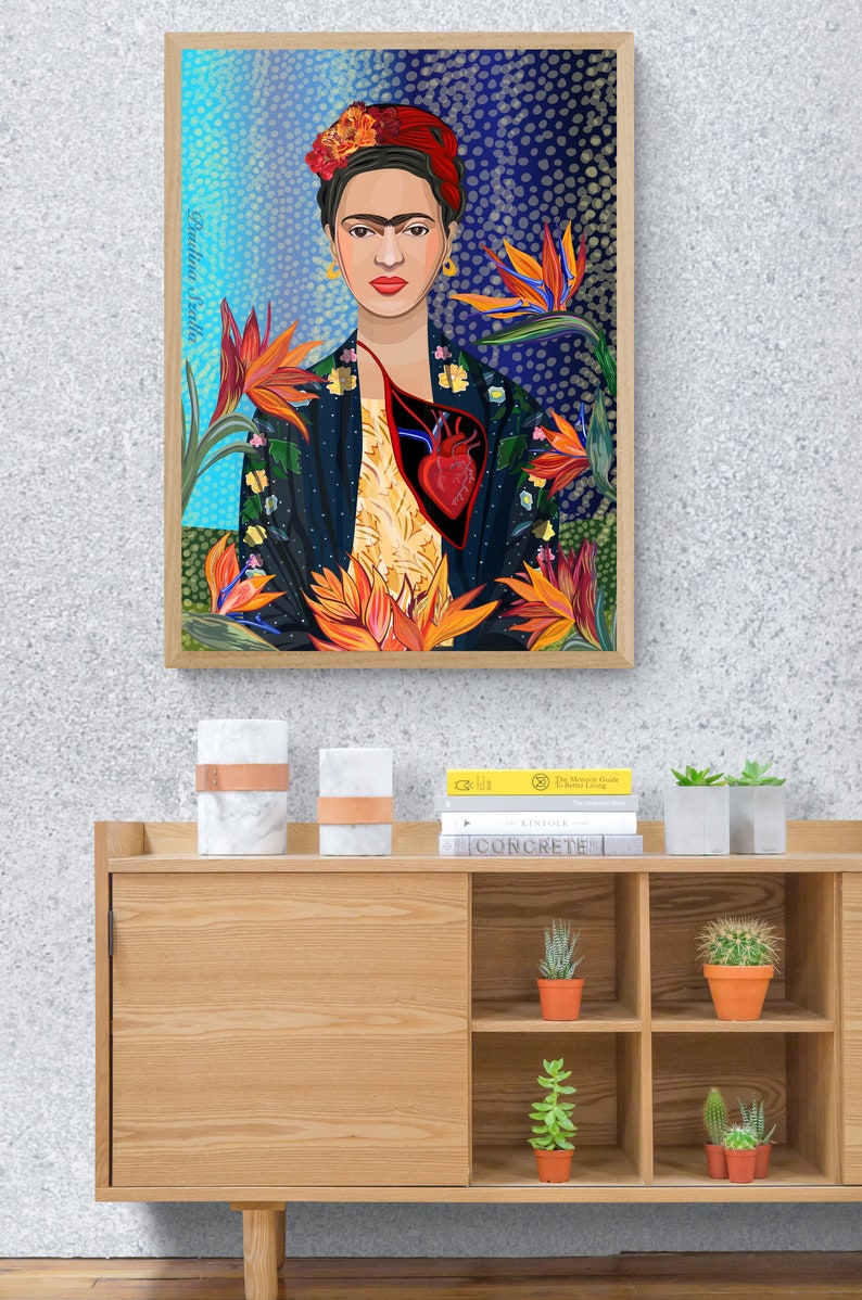 May include: A framed print of a colorful illustration of Frida Kahlo with a heart in her chest and flowers surrounding her. The text "Frida Kahlo" is written vertically on the left side of the frame.