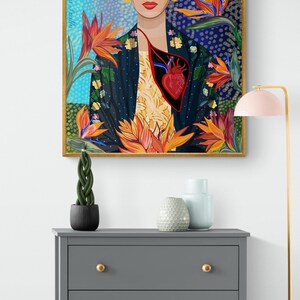 May include: A framed illustration of Frida Kahlo with a red heart and flowers. The background is a blue and white pattern.