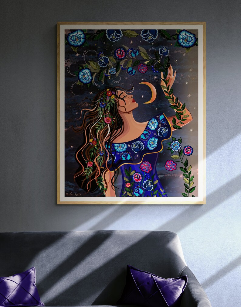 May include: A digital illustration of a woman with long brown hair wearing a blue dress with floral embroidery. She is reaching up towards a crescent moon with stars in the background. The artwork is framed in a wooden frame.