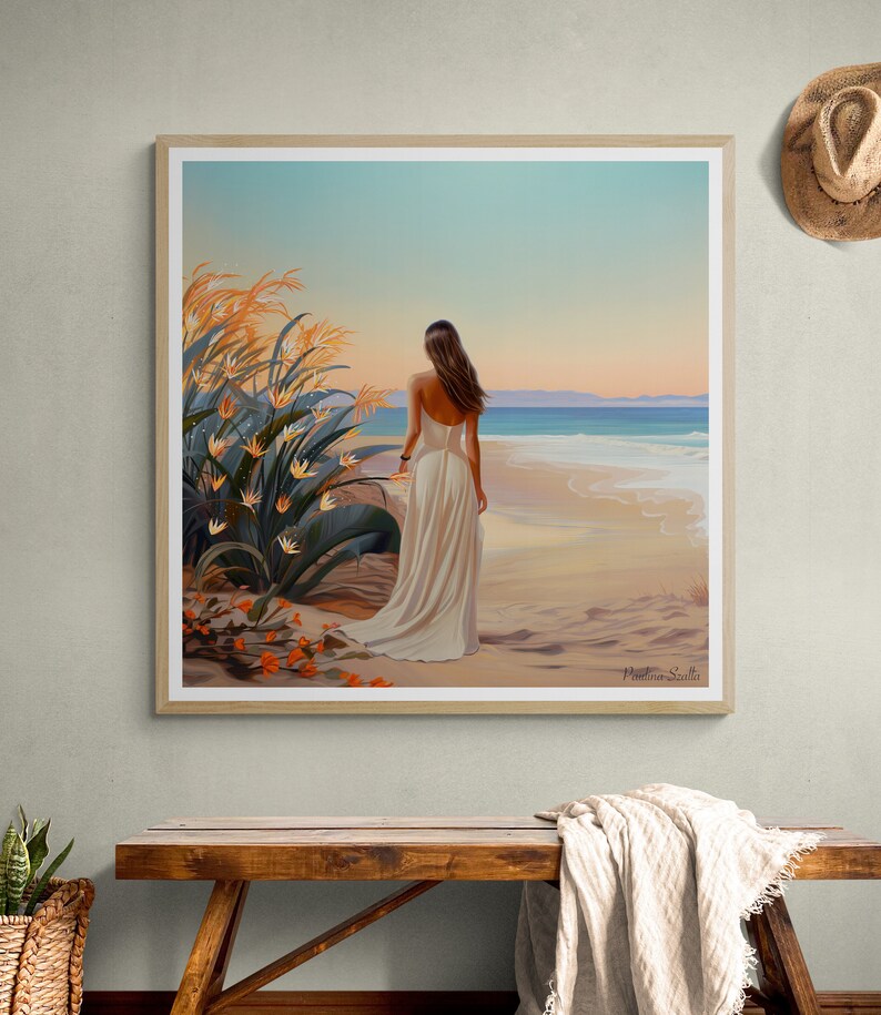 May include: A woman in a white dress walks along a sandy beach with her back to the viewer. The ocean is in the background and there are tall green plants with orange flowers in the foreground. The sky is a light blue with a hint of pink.