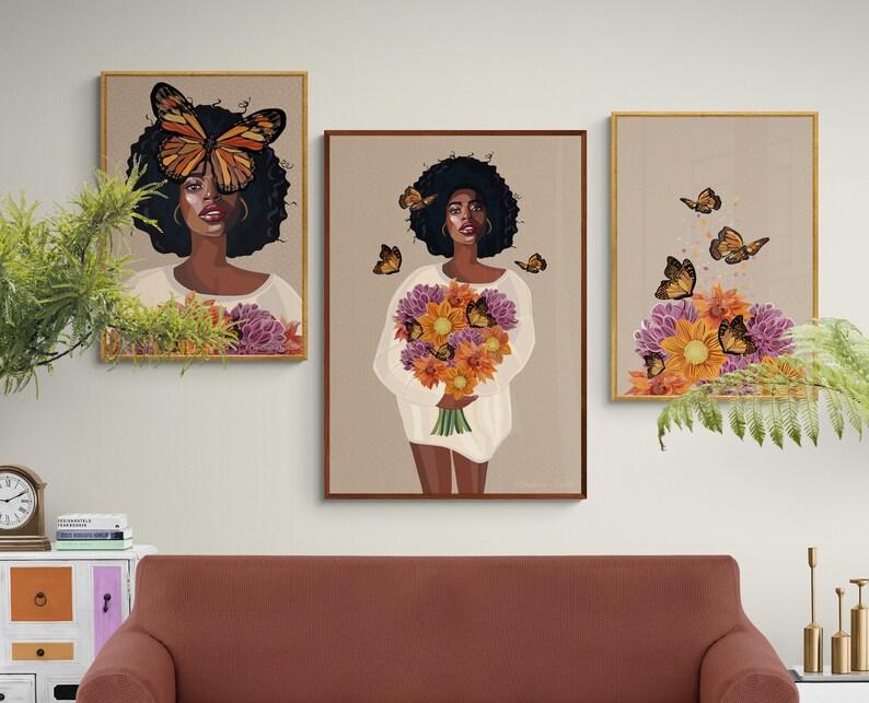 Puede incluir: Tres impresiones de arte enmarcadas que representan a una mujer con una mariposa sobre los ojos, un ramo de flores y un arreglo floral con mariposas. Las impresiones est&aacute;n en marcos dorados y tienen un fondo marr&oacute;n claro.
