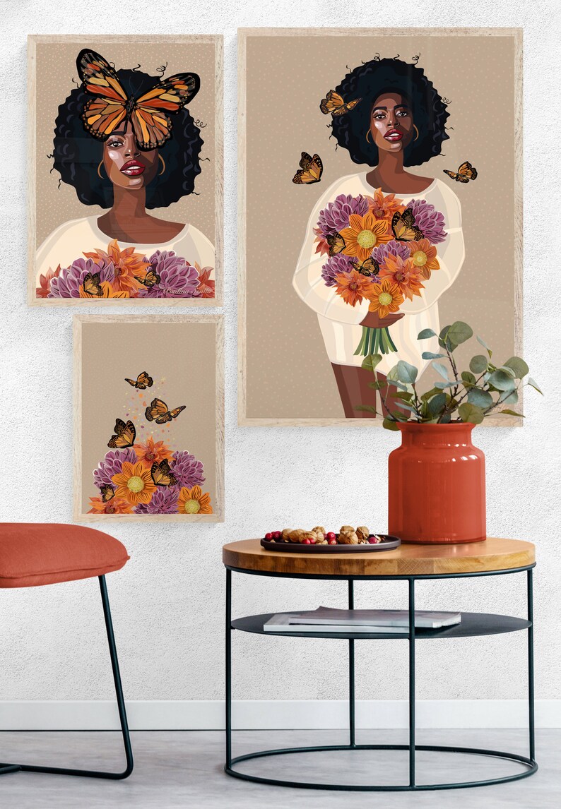 Puede incluir: Tres impresiones enmarcadas con una mujer de cabello oscuro y una mariposa sobre sus ojos sosteniendo un ramo de flores. La mujer lleva una camisa blanca. Las impresiones est&aacute;n en una pared blanca con una mesa de madera y un jarr&oacute;n rojo con una planta verde.