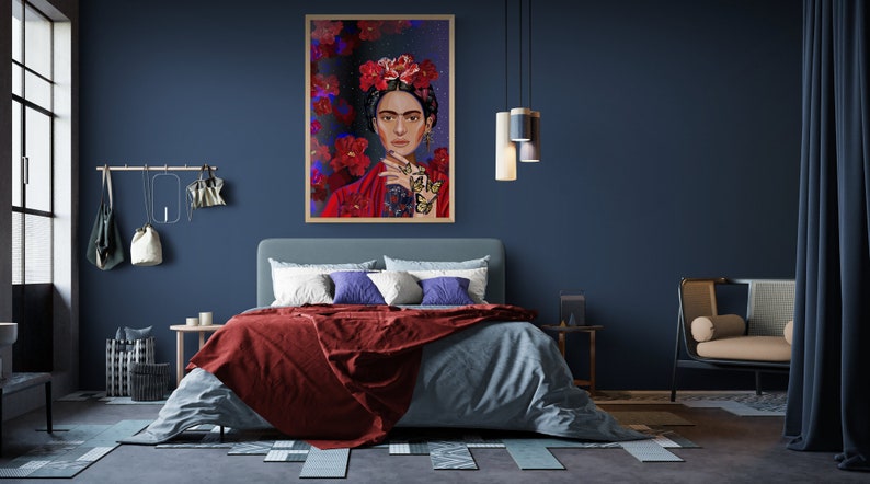 May include: A bedroom interior with a blue wall, a bed with a red and blue blanket, a framed painting of a woman with flowers in her hair, and a chair in the corner.
