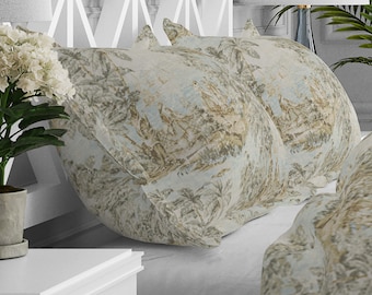 May include: Two beige pillowcases with a light blue and brown patterned design featuring a landscape scene. The pillowcases are on a white bed with a matching patterned duvet cover.