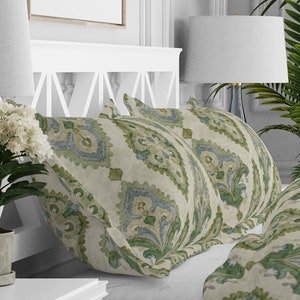May include: Two decorative throw pillows with a green and blue paisley pattern on a white background.