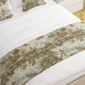 May include: A white bed with a beige and green patterned bed runner featuring a hunting scene. The runner has a repeating pattern of trees, a river, and people hunting with dogs.