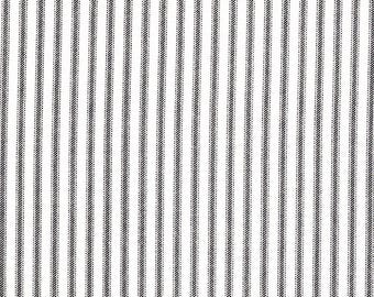 May include: White fabric with vertical black pinstripes. The stripes are evenly spaced and run the entire length of the fabric. The fabric has a slightly textured appearance.