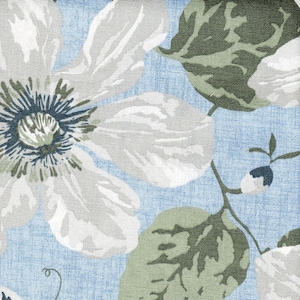 May include: A blue fabric with a white floral pattern. The flowers have a green center and are surrounded by green leaves.