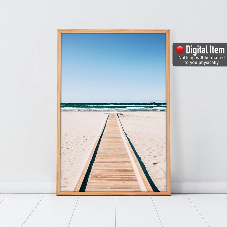 Puede incluir: Una impresi&oacute;n digital de una pasarela de madera que conduce al oc&eacute;ano. La pasarela se encuentra en una playa de arena blanca con agua azul y un cielo azul claro de fondo.