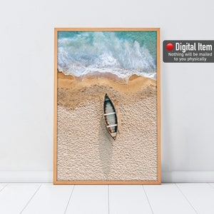 May include: An aerial view of a small wooden boat on a sandy beach with turquoise water and white waves in the background.