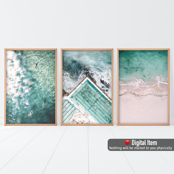 May include: A set of three digital prints featuring aerial views of a beach, ocean, and a pool. The prints are framed in wood and have a light, airy feel.