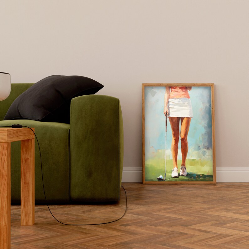 May include: A framed painting of a woman in a white skirt and pink shirt holding a golf club. The painting is set against a green grassy background with a blue sky.