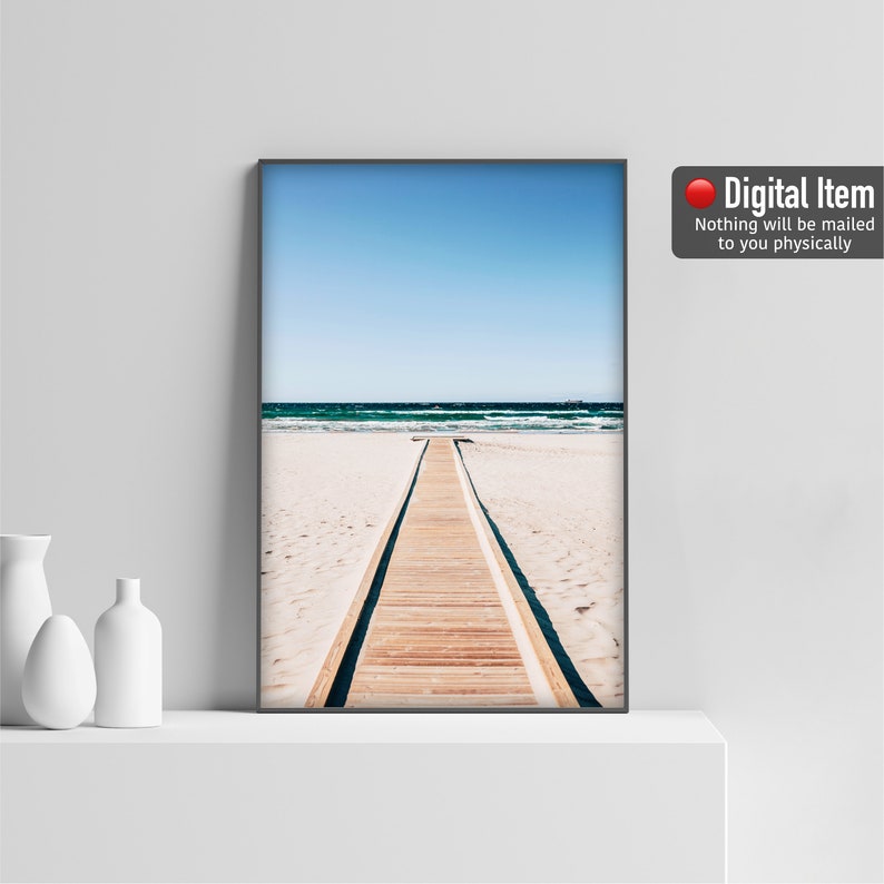 Puede incluir: Una impresi&oacute;n digital de una pasarela de madera que conduce al oc&eacute;ano. La pasarela se encuentra en una playa de arena blanca con agua azul y un cielo despejado en el fondo.