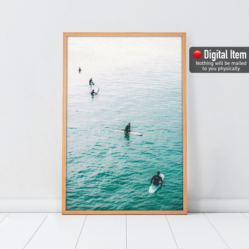 May include: A framed print featuring a serene ocean scene with several surfers. The turquoise water contrasts with the light brown frame. The text "Digital Item" and a disclaimer are visible on the right side.