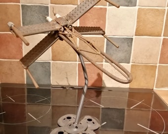 May include: A metal sculpture of a spaceship with a rusted finish. The spaceship is mounted on a metal stand with a circular base.