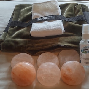 May include: A set of six pink Himalayan salt stones, a green velvet pouch with a zipper, a white washcloth, and a clear bottle with a white label that says "Shower 30 Detox" in black text.
