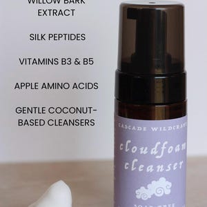May include: A brown bottle of Cascade Wildcraft cloudfoam cleanser with a black pump top. The label is light purple with white text and a cloud graphic. A dollop of white foam sits next to the bottle. The ingredients include Lavender Hydrosol and Willow Bark Extract.
