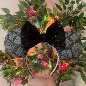 May include: Black sequin bow headband with grey and white fabric ears. The ears feature a Halloween theme with images of pumpkins, spiders and bats. The text "Vampire Fangs" and "Pumpkins" are visible on the ears.