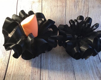 May include: Two black satin hair bows with a ruffled design. The larger bow is on the left and the smaller bow is on the right.