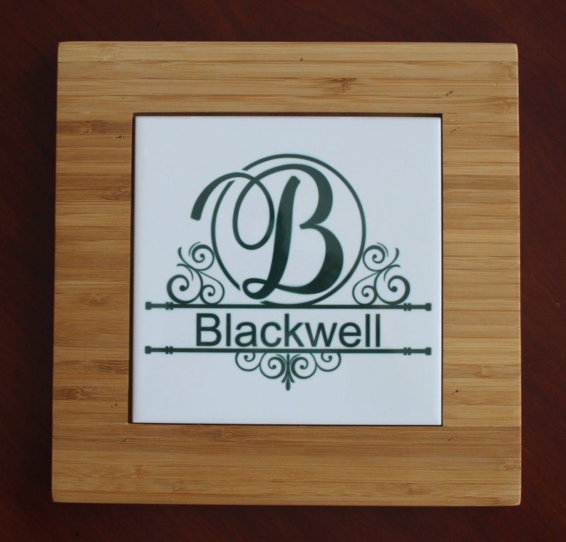 May include: Square bamboo coaster with a white tile insert. The tile features a dark green monogram "B" with decorative flourishes and the name "Blackwell" below. The coaster has a natural wood grain finish.
