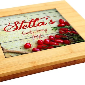 May include: A rectangular bamboo serving tray with a central image featuring the text "Stella's family dining NYC". The image includes red peppers, rosemary, and a wooden spoon on a distressed wood background. The tray has a natural wood finish.
