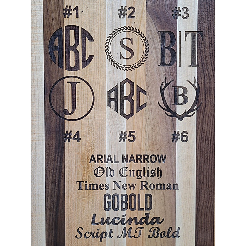 Pu&ograve; includere: Un tagliere in legno con sei diversi stili di font visualizzati. I font sono Arial Narrow, Old English, Times New Roman, Gobold, Lucinda e Script MT Bold. Il tagliere &egrave; in legno di acero e noce.