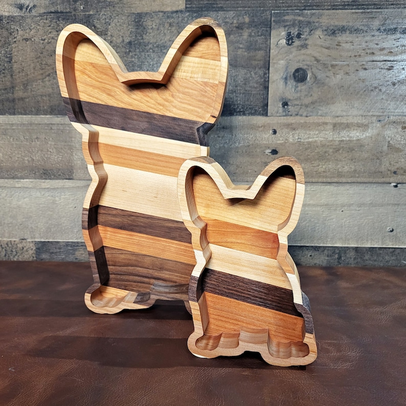 Pu&ograve; includere: Due vassoi da portata in legno a forma di Bulldog francese. Il vassoio pi&ugrave; grande &egrave; marrone, beige e marrone chiaro con un contorno marrone pi&ugrave; scuro. Il vassoio pi&ugrave; piccolo &egrave; beige, marrone chiaro e marrone scuro con un contorno marrone pi&ugrave; scuro.
