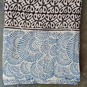 May include: A white cotton scarf with a blue and white paisley pattern. The scarf has a gold trim around the edges.